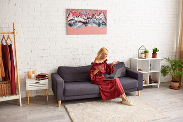 Fototapeta premium Sophisticated woman in stylish dress on a living room couch.