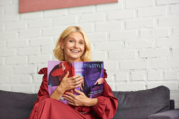 A sophisticated woman in stylish attire sits on a couch, engrossed in a captivating magazine.