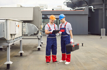 Team of positive workmen with equipment repairing and servicing the ventilation and climate control...