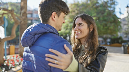 A loving couple embraces on a sunny urban street, exuding warmth and happiness.