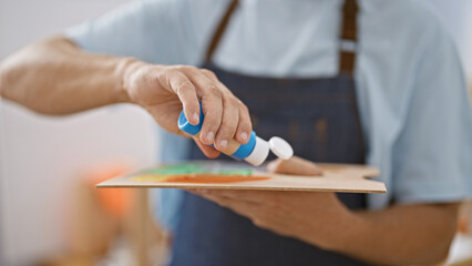 Close-up of a man's hands pouring glue onto a palette in an art workshop setting, demonstrating creativity and craftsmanship.