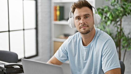 Fototapeta premium Portrait of a young hispanic man with headphones in a modern indoor setting, conveying a casual professional or academic vibe.