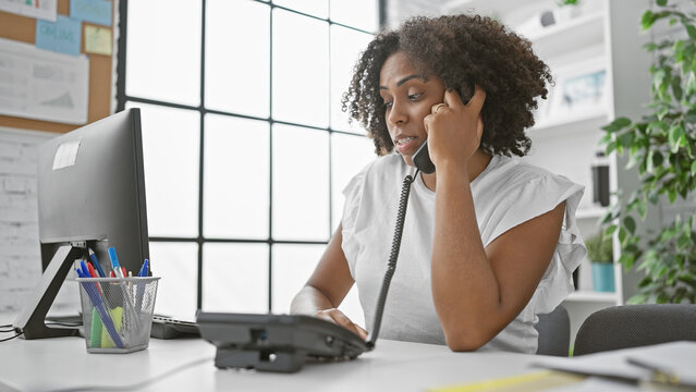 African american woman with braids speaking on phone in office