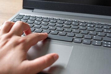 Clavier d'ordinateur portable sur un bureau en bois, main qui tape sur un clavier d'ordinateur