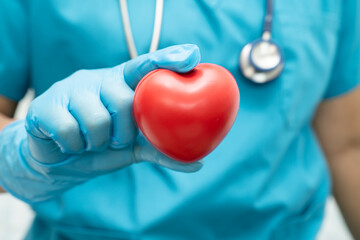 Doctor holding a red heart in hospital ward, healthy strong medical concept.