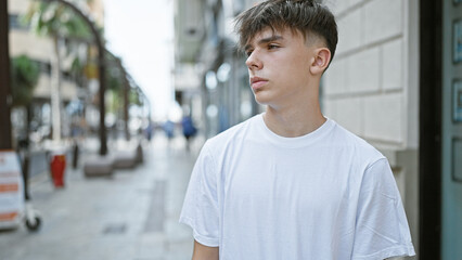 Obraz premium Caucasian teenage boy with blond hair wearing a white t-shirt on a city street