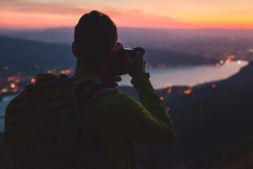 photographer taking picture of Annecy lake in France at twilight, night photography, silhouette of man with backpack and dslr camera