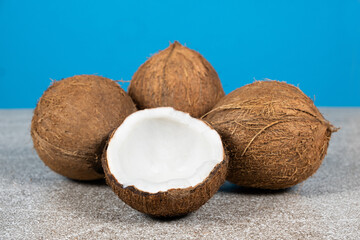 Whole coconuts and half a coconut on a blue and gray background close-up