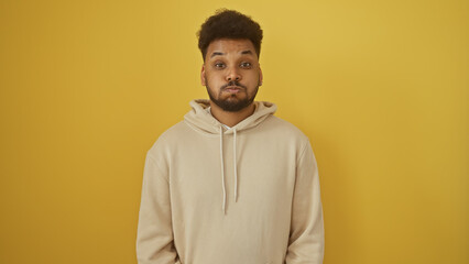 Portrait of a handsome adult african american man wearing a hoodie against a yellow background.