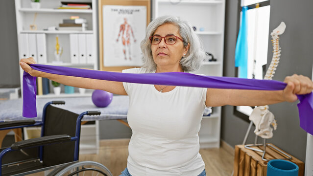 Mature woman exercises with resistance band in a rehabilitation clinic.