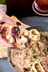 female hand close up on toast with seafood cream octopus squid shrimp seafood macro