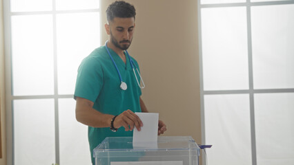 A young hispanic man casts his vote in an electoral college room, depicted in an indoor setting...