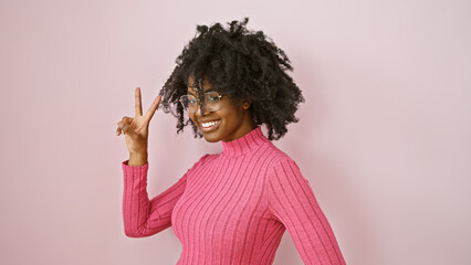 African american woman posing playfully in a pink sweater against a light background