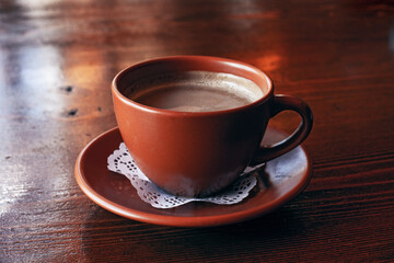 Fresh Americano coffee with milk in traditional  brown clay cup  on the wooden table