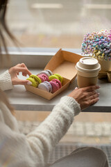 Pretty woman a sweater with a craft glass of coffee in her hand and macarons
