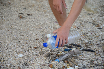 Young man volunteer cleaning tropical beach from plastic pollution. Close up.