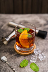 Fresh made Cuba Libre cocktail with ice cube, rum, cola, mint and lemon on wooden background