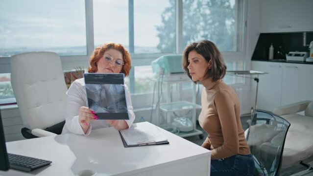 Woman radiologist showing x-ray to focused patient in medicare office closeup. 