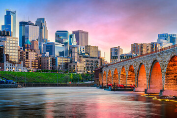 Minneapolis, Minnesota, USA skyline with the Stone Arch Bridge on the Mississippi River at dusk.