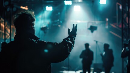Silhouette of a director giving instructions to the crew under stage lights