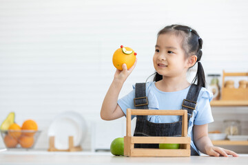 cute asian little child girl holding green apples in the kitchen