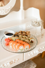Set of sushi rolls with a saucer of soy sauce on a transparent glass plate