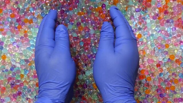 Hands slowly collect a lot of multicolored orbis in the palms. Fingers squeeze the colored, shiny orbis and smoothly spread downwards against the background of a multitude of orbis. ASMR Part12.14