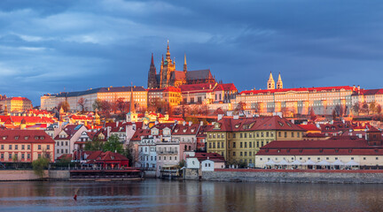Fototapeta premium A ray of sun unexpectedly illuminated Prague Castle against the backdrop of a blue cloudy sky