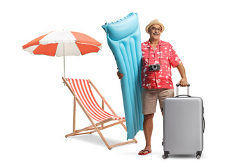 Male tourist with inflatable mattress and a suitcase next to a beach chair and umbrella