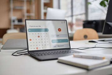Close up shot of laptop at workplace table. Computer screen displaying calendar with month of May, focus on screen, copy space