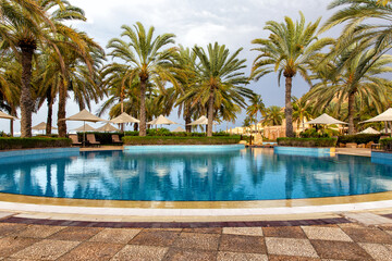 Swimming pool with clear water surrounded by palm trees in one of the best resorts