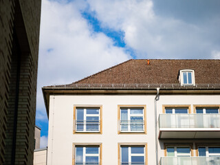 Residential building with windows in a city in Germany. Close up of the facade and the rooftop. The apartment house was built in the 1950s.