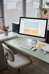 Clean and minimalist home office setup desktop PC with bright screen displaying online course platform. Comfortable setting and productive workspace