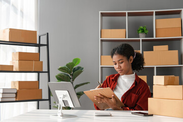 Female Small Business Owner Managing Online Sales from Home Office with Tablet and Shipping Boxes, Entrepreneur Working on E-commerce Business, Modern Workspace with Plants and Shelves
