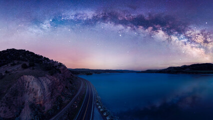 Full Milky Way arch panorama over a lake and reflecting off the water