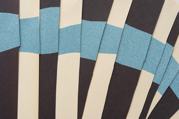 overlapping white and black construction paper stripes with blue vinyl glitter material