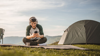 Young boy sit on blanket on the mountain listen music on headphones