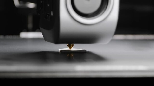 A portal with a carriage and a print head of a 3D printer that prints with white plastic on a printing platform. additive manufacturing concept