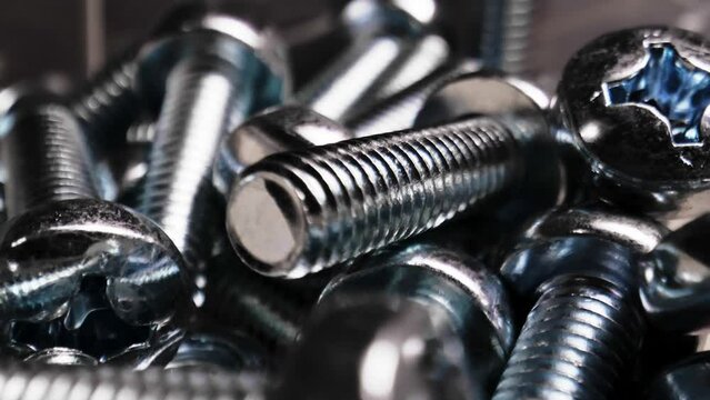 Chrome bolts close up. A bunch of bolts are scattered on the table.