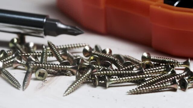 screws on a wooden table against a background of a screwdriver and nozzles set. screws close-up.