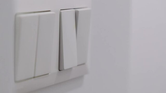 Finger switching on wall-mounted light switch. Power, energy and electricity consumption.