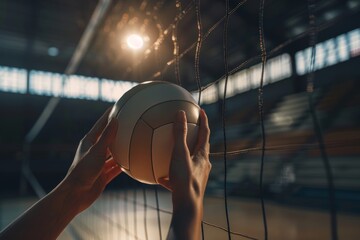 Close-up of hands holding a volleyball at the net in an indoor court under stadium lights, capturing the essence of the sport.