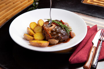 Osso buco with baked potatoes in a plate.