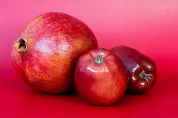 Pomegranate and apples on a red background. Healthy food.