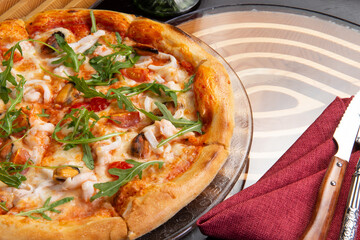 Pizza with seafood and arugula in a plate.