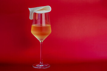 A glass of wine on a red background with a cheese