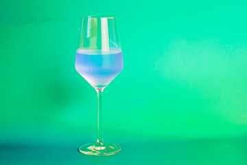 Blue cocktail in a glass on a green background. Copy space.