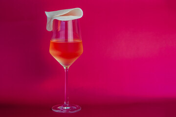 Cocktail in a wine glass on a pink background with copy space