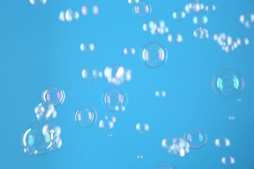 Beautiful transparent soap bubbles on light blue background