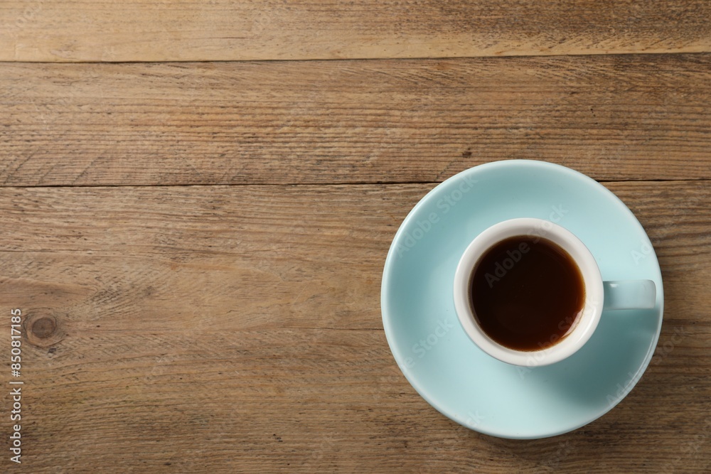 Poster Tasty coffee in cup on wooden table, top view. Space for text